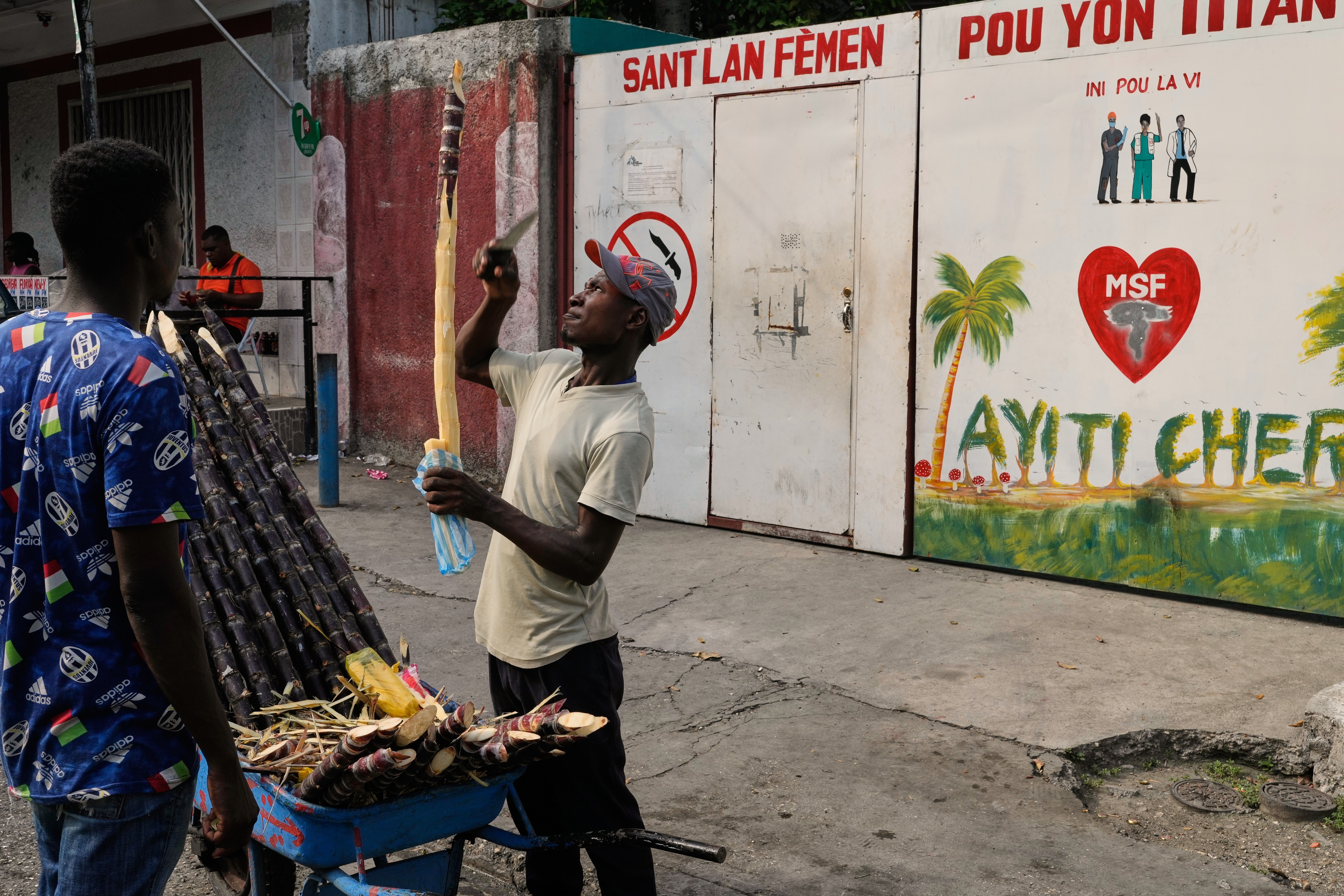 A vendor sells sugarcane next to the entrance of the Doctors Without Borders (MSF) clinic in Port-au-Prince, Haiti, Wednesday, Oct. 15, 2025, after the organization announced the facility